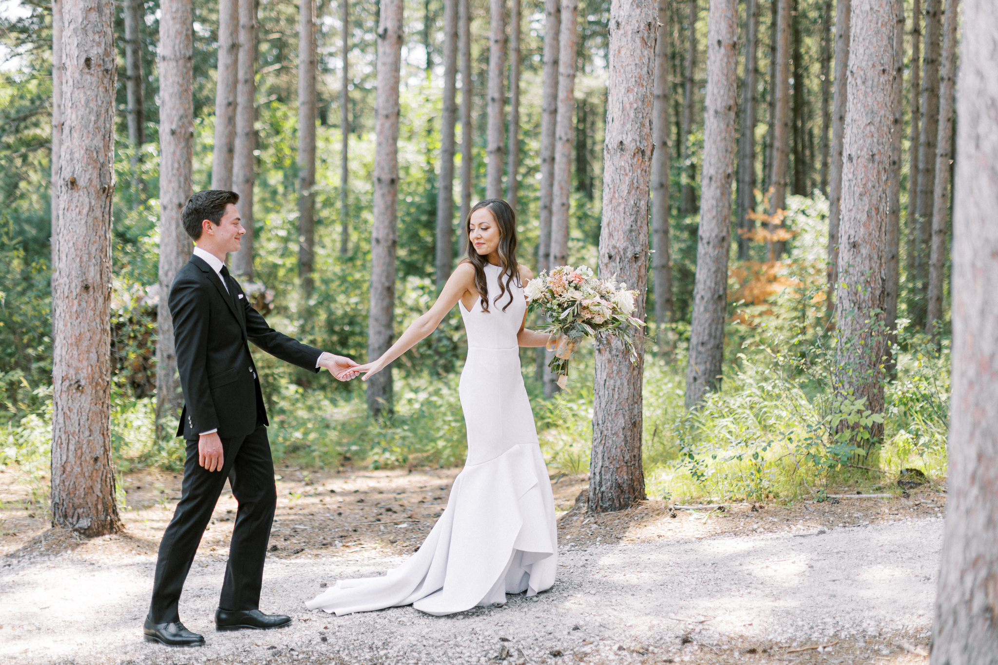 Bride and Groom walk in the pines at Pinewood Wedding Venue